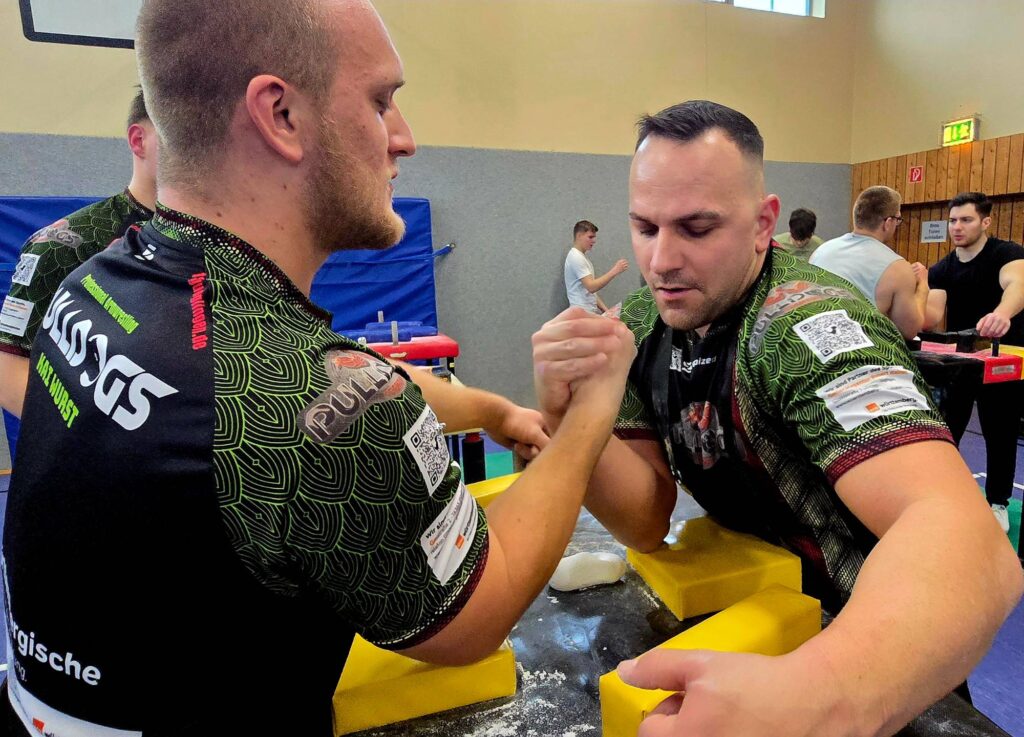 Zwei Armwrestler der Pulldogs Germany im Griff am Wettkampftisch in der Sporthalle