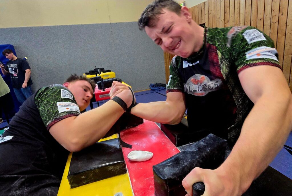 Zwei Armwrestler der Pulldogs Germany im Kampf mit Gurt am Wettkampftisch